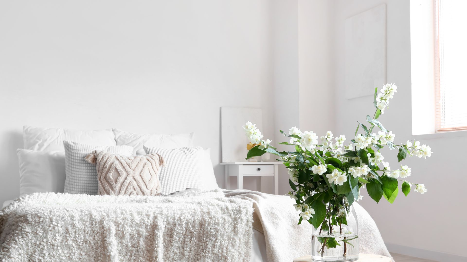 花とベッドのある白っぽいインテリアの部屋